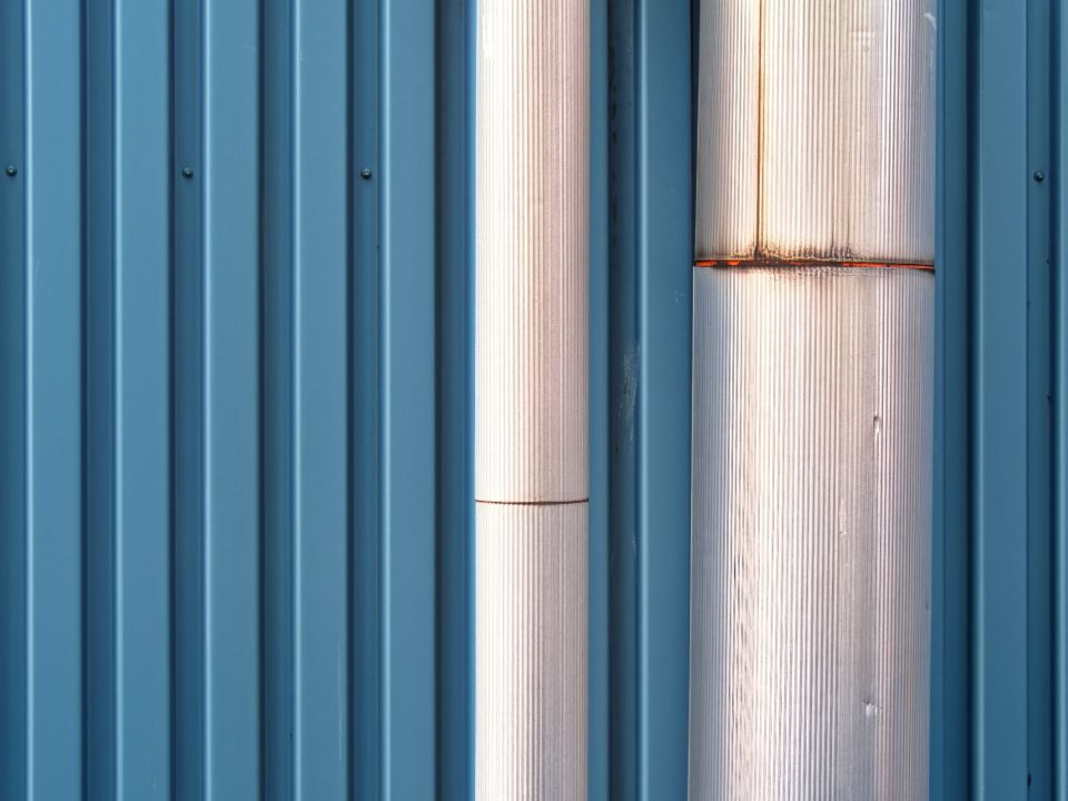 Metal pipe running down a blue exterior wall